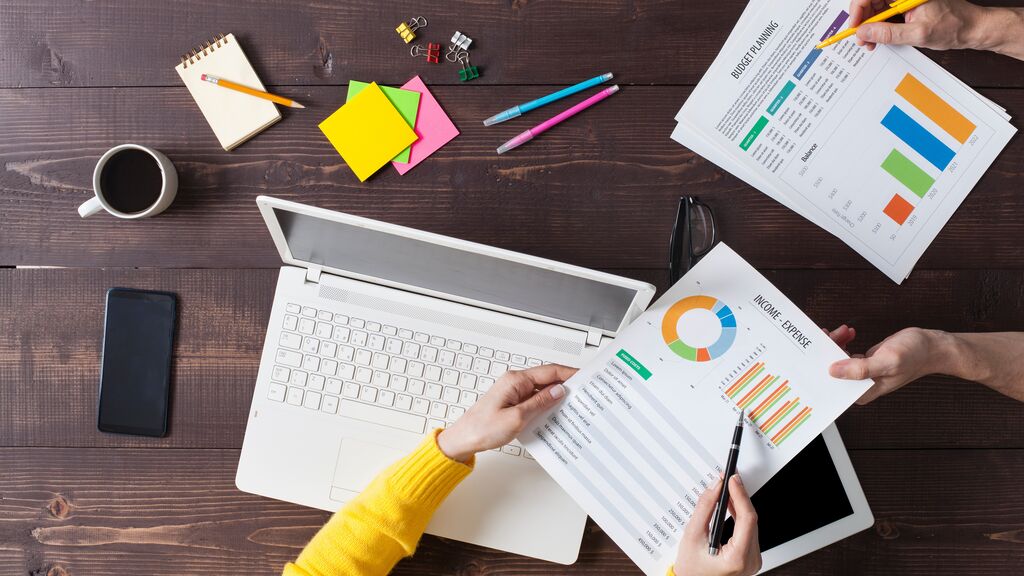 Two people working on desk at office. Overhead shot.